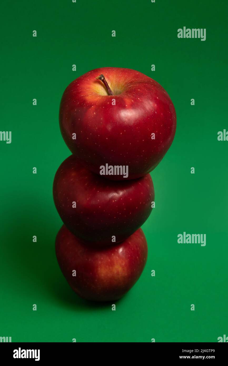 Three red delicious apples on green background Stock Photo