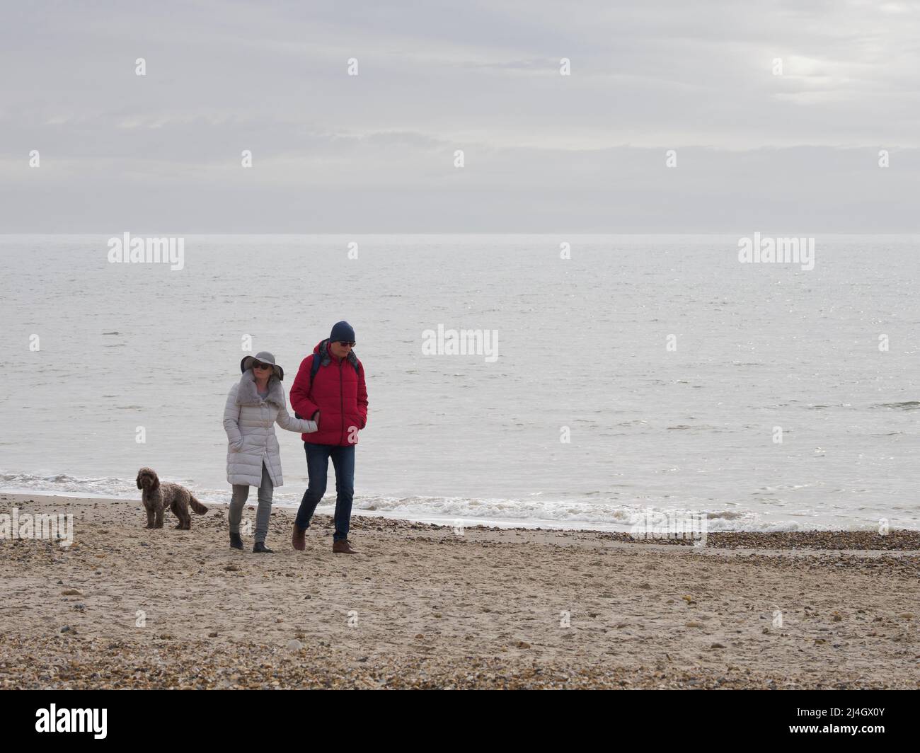 Couple walking along the beach in March, Highcliffe, Dorset, UK Stock Photo
