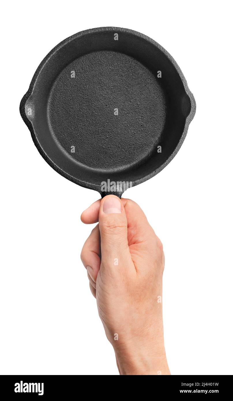 Hand holding black cast-iron frying pan, isolated on white background Stock Photo