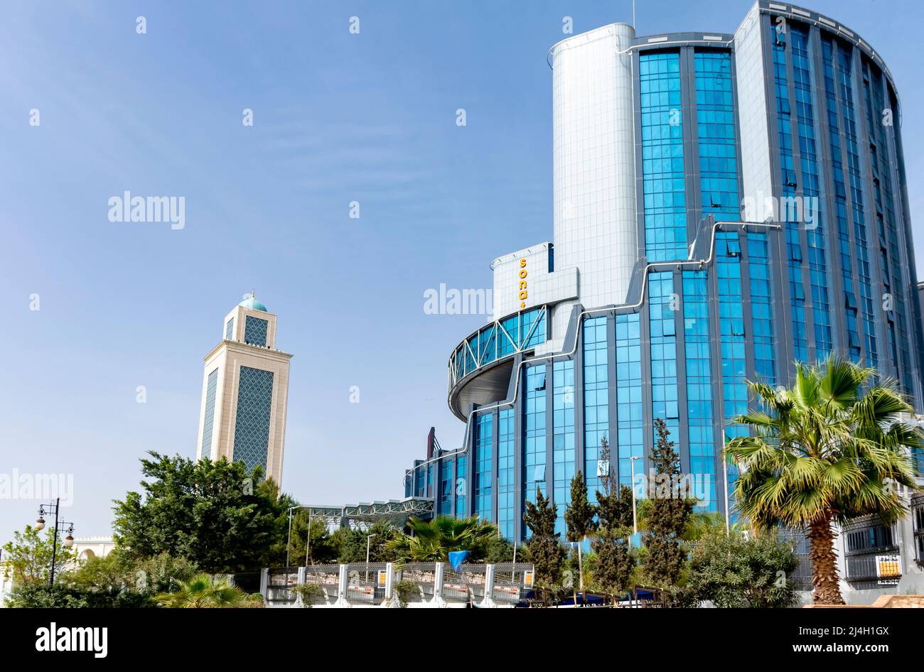 Sonatrach AVAL  and Grand Mosque Abdelhamid Ibn Badis minaret. Headquarters of the Sonatrach company, a low angle view of the modern buildings. Stock Photo