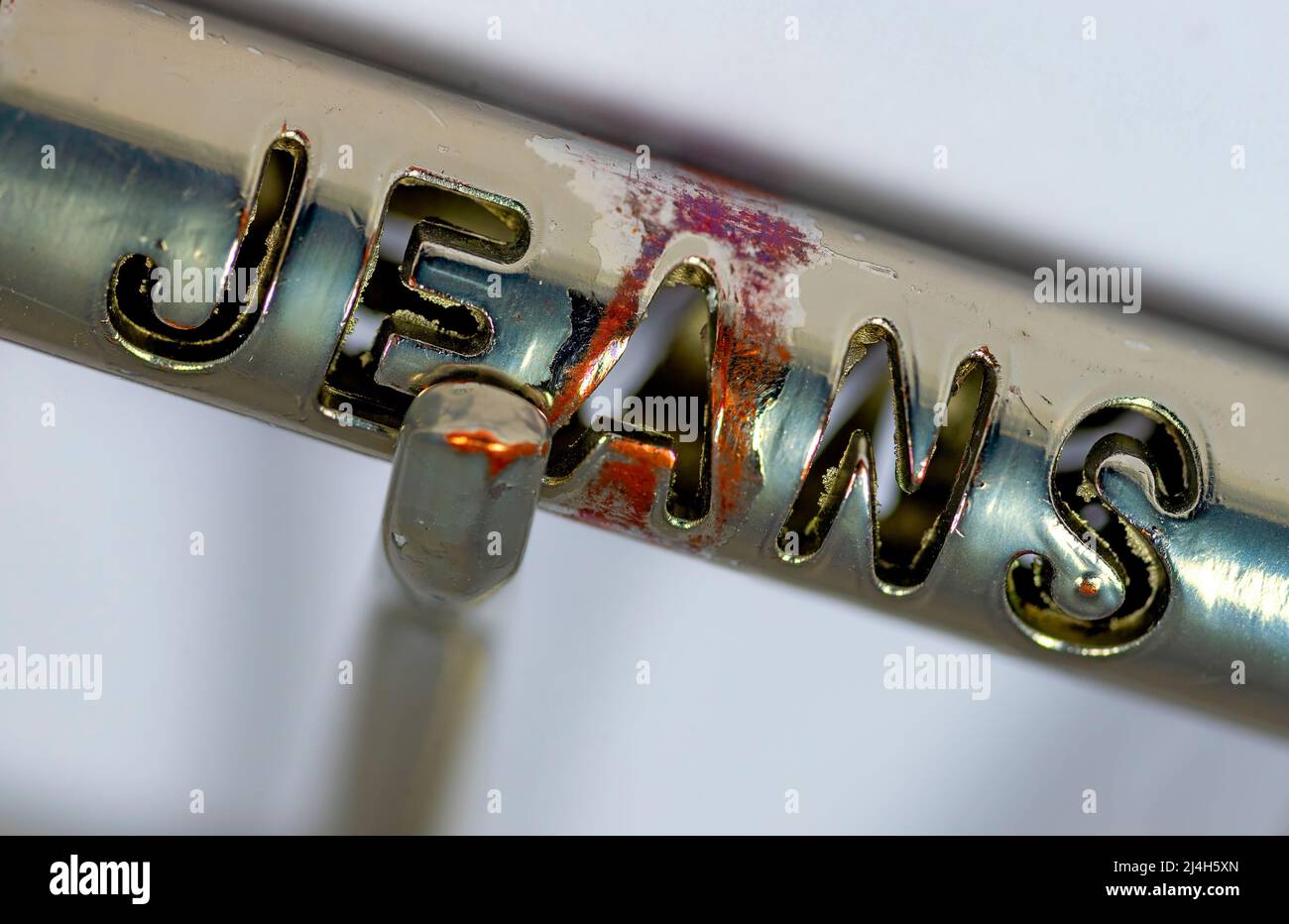 near view of the punched out word 'JEANS' on an used metallic belt buckle Stock Photo