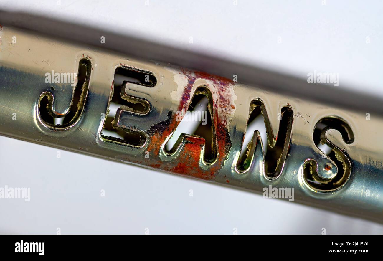 near view of the punched out word 'JEANS' on an used metallic belt buckle Stock Photo
