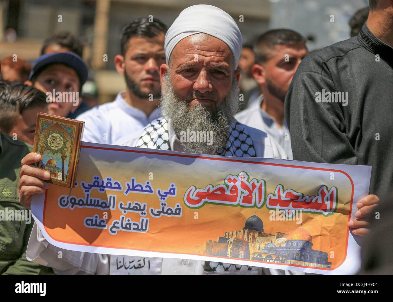 Gaza, Palestine. 15th Apr, 2022. A Palestinian man holds the Quran and a banner as he participates in a solidarity demonstration with worshipers at Al-Aqsa Mosque in Khan Yunis in the southern Gaza Strip. Clashes erupted between the Israeli security forces and the Palestinians in Jerusalem (worshipers at Al-Aqsa Mosque), in light of the escalation of tensions during the past weeks in the West Bank and Jerusalem. Credit: SOPA Images Limited/Alamy Live News Stock Photo