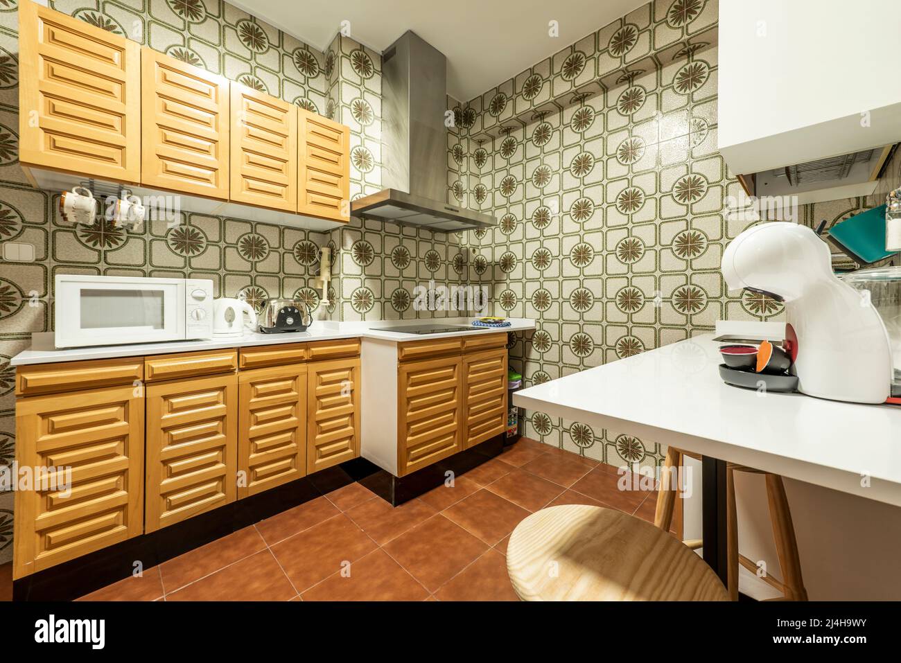 Kitchen with white stone countertops, solid wood cabinets, and vintage tile  on the walls Stock Photo - Alamy