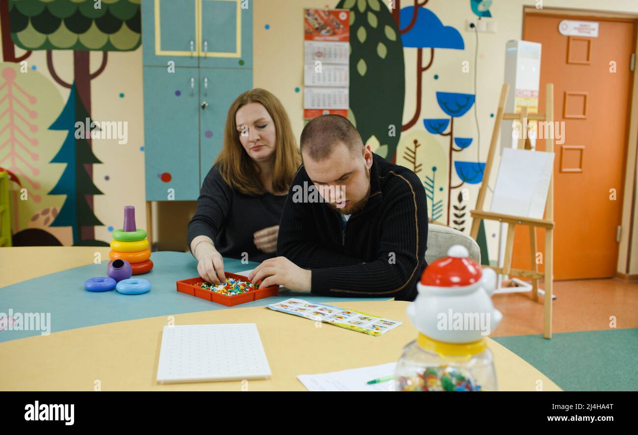 A female psychologist works with an adult boy with autism in the office. The concept of autism