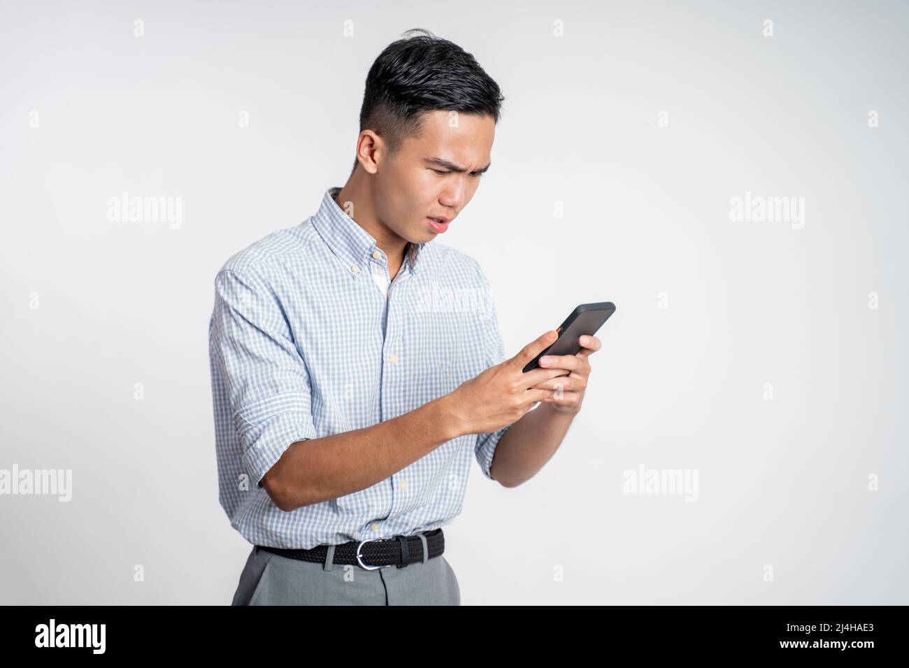 confuse young businessman while looking at his smartphone Stock Photo