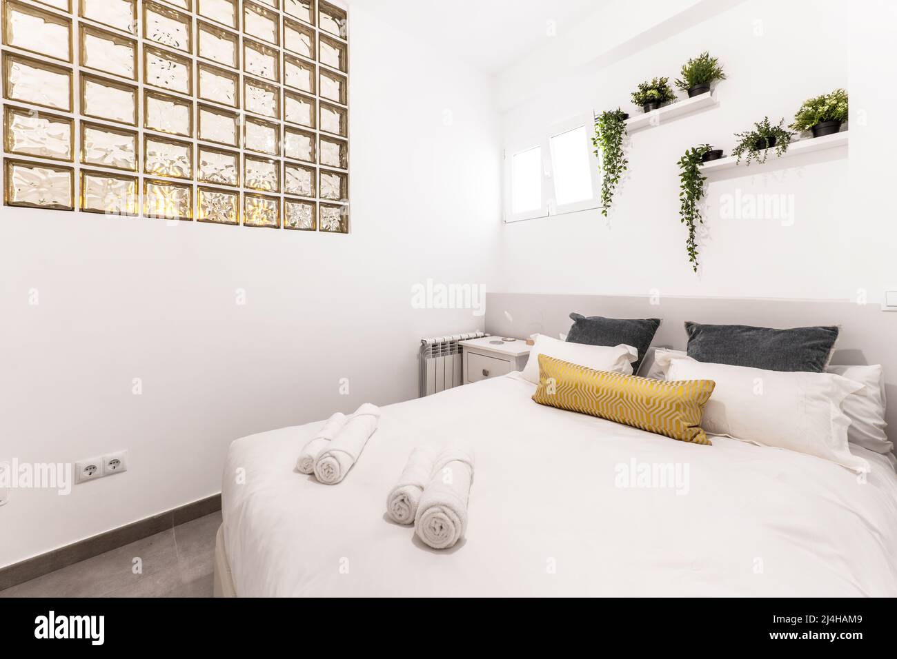 Double bed with blue, gold and white pillows and cushions, rolled white