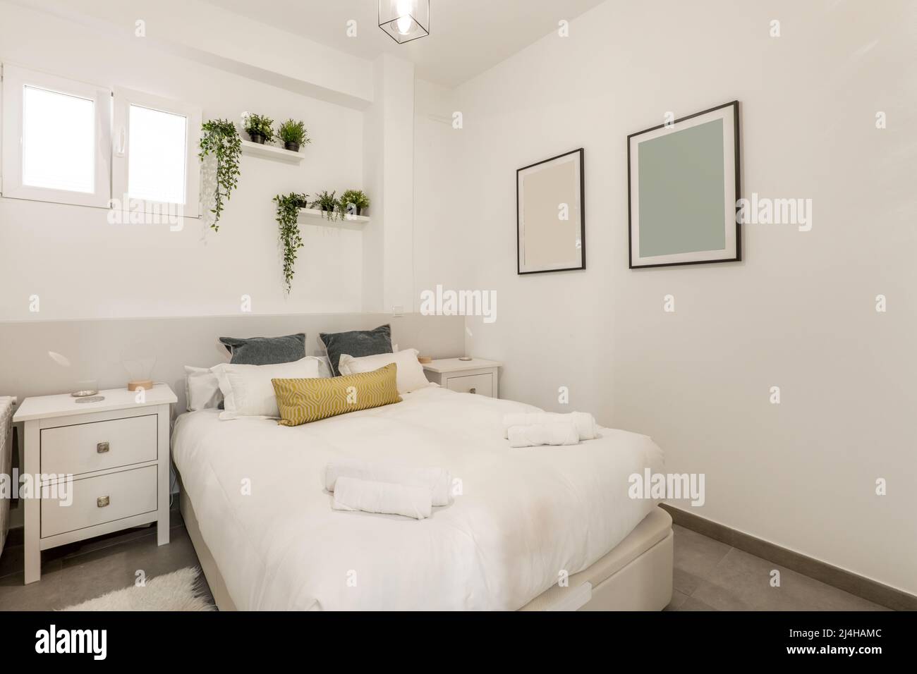 Double bed with blue, gold and white pillows and cushions, white rolled