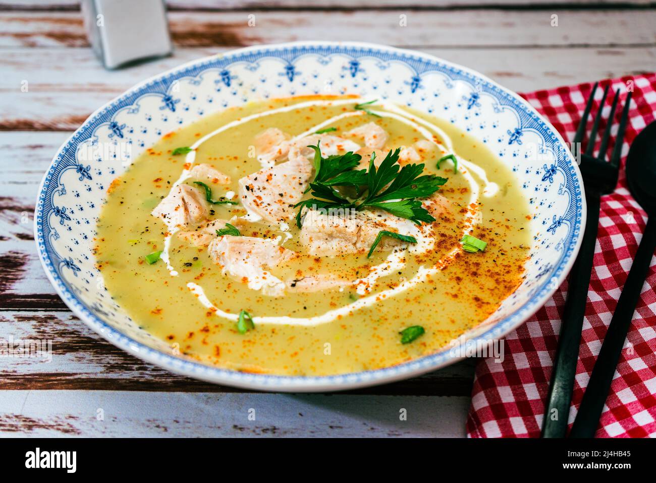 Exquisite dish with a homemade cream of poultry soup with chicken pieces, parsley and cream on a rustic or country style wooden table. Natural and sim Stock Photo