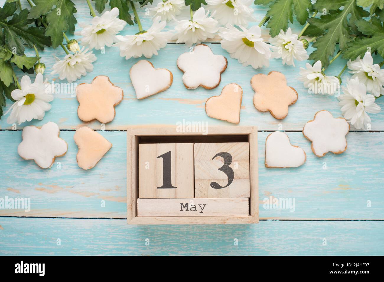 Texture of a tree with yellow flowers and homemade cookies in the form of a month with a calendar on which May 13, the International Mother's Day. Top Stock Photo