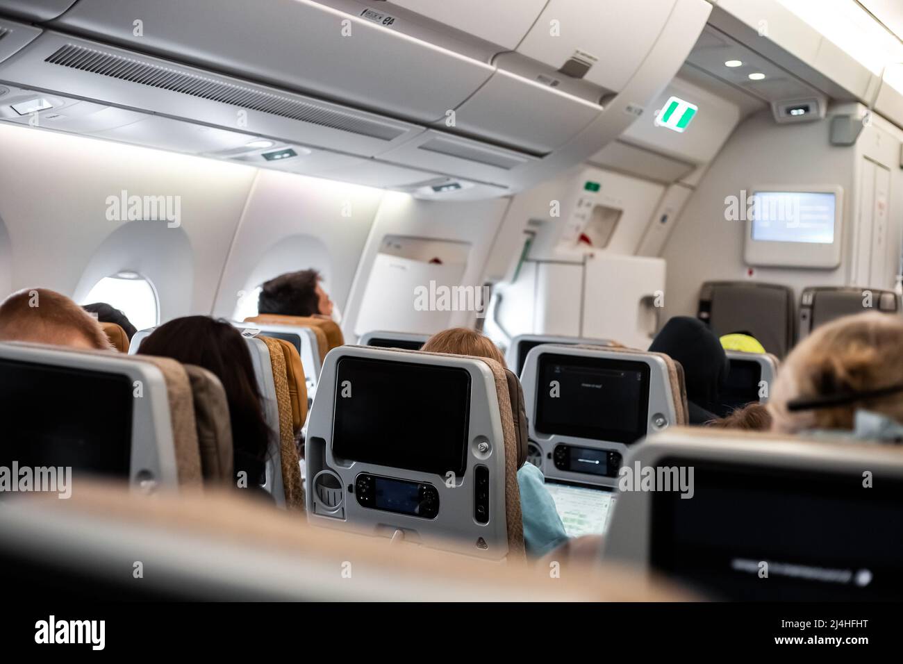 The passenger cabin of the aircraft with people in the chairs. Comfortable flight conditions on an international flight. Stock Photo