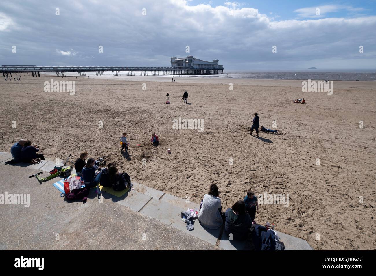 Holiday makers enjoy the beach at Weston Super Mare with the Grand Pier in the Bristol Chanel, Somerset. Stock Photo
