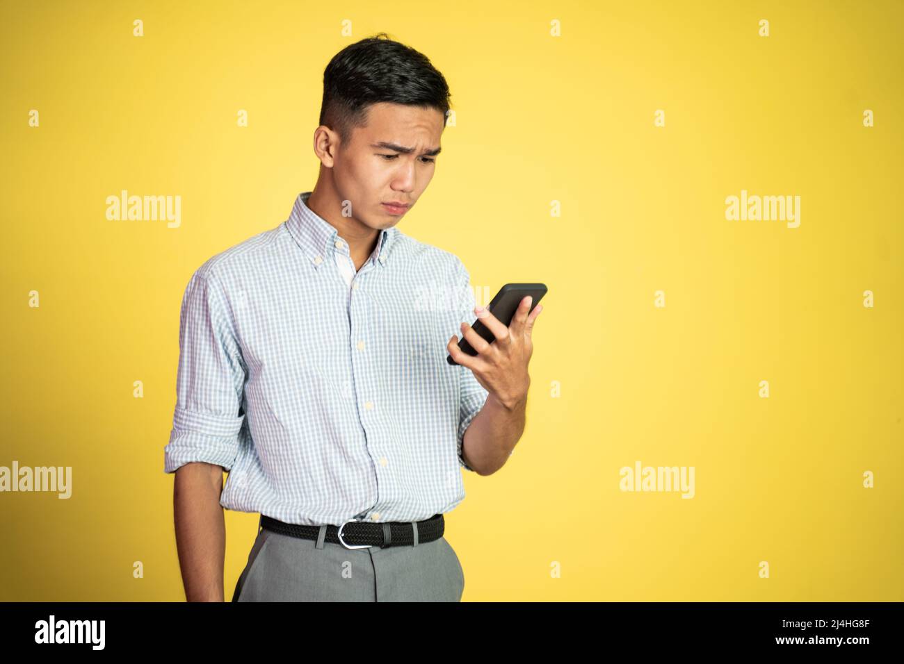 confuse young businessman while looking at his smartphone Stock Photo