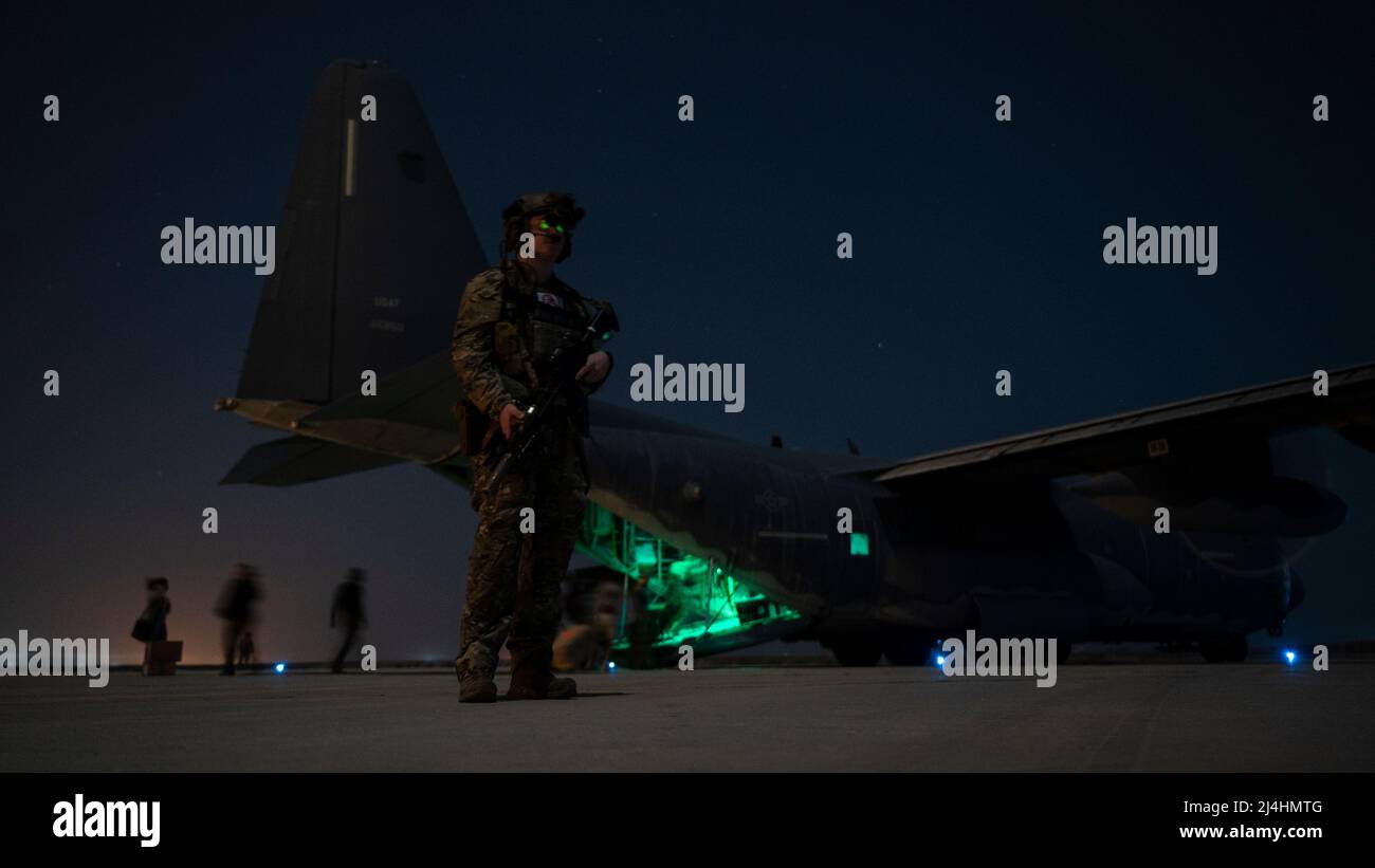 A Deployed Aircraft Ground Response Element member stands guard as U.S. special operators load onto an MC-130J Commando II assigned to the 9th Expeditionary Special Operations Squadron at an undisclosed location in the U.S. Central Command area of responsibility, Nov. 19, 2021. The MC-130J provides infiltration, exfiltration and resupply of special operations forces and equipment in hostile or denied territory. Secondary missions include psychological operations, and helicopter and vertical lift air refueling. (U.S. Air Force photo by Staff Sgt. Joseph Pick) Stock Photo