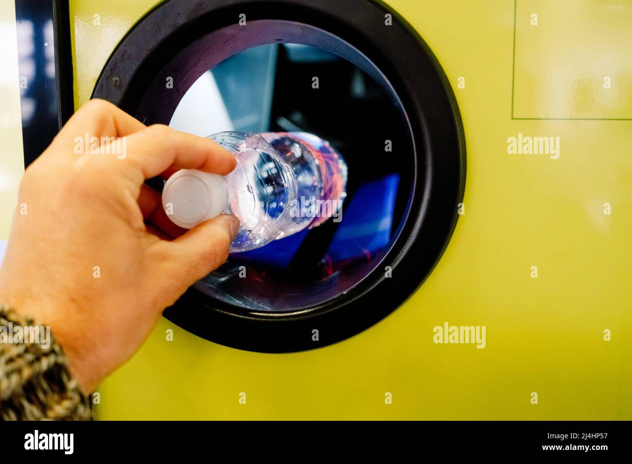 Man puts a plastic bottle in a recycling machine in exchange for