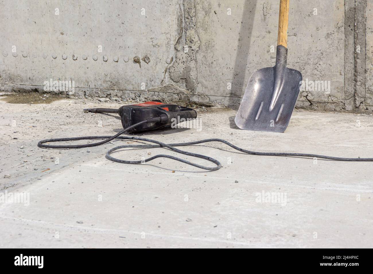 a hammer drill with a nozzle a flat chisel lies on the concrete surface
