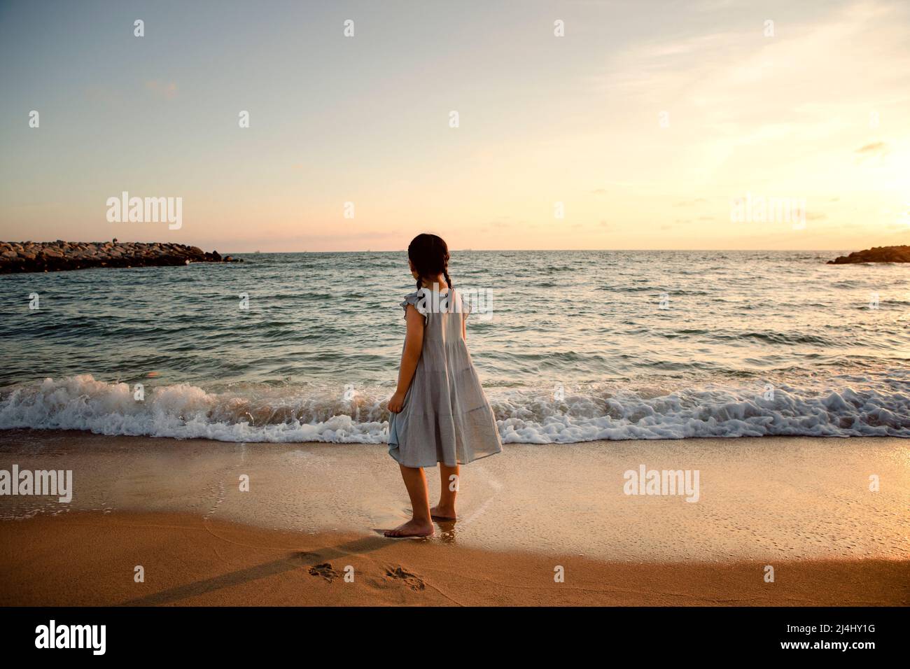 girl children standing at sea beach against beautiful sunset light Stock Photo