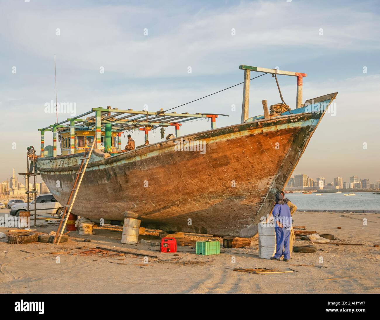 Men renovating a wooden dhow in Al Khan, in the the city of Sharjah, United Arab Emirates. Stock Photo