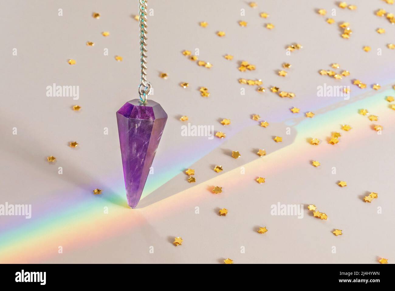 Amethyst pendulum over rainbow Stock Photo