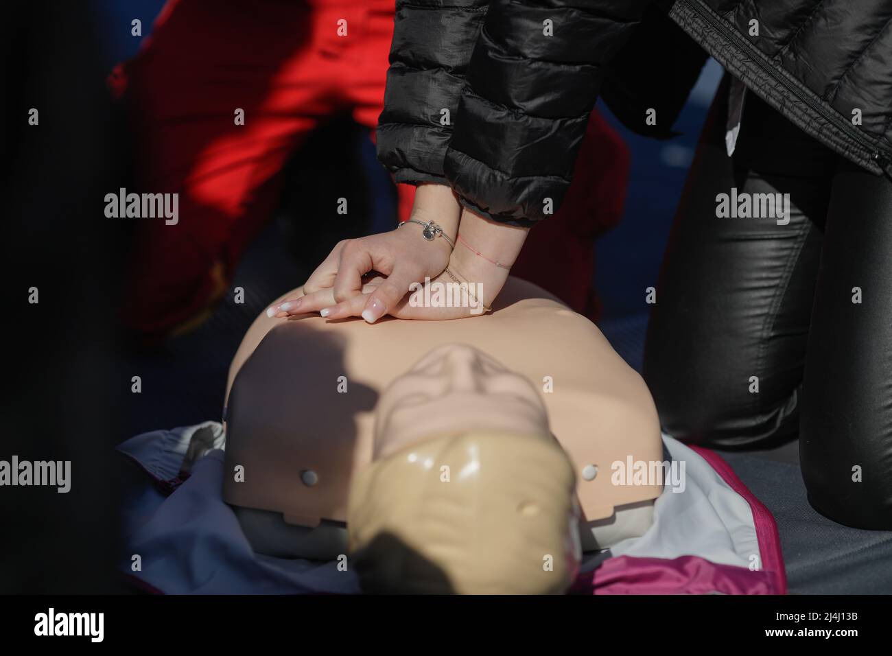 Details with the hands of an emergency medical services worker performing cardiopulmonary resuscitation (CPR) on a mannequin for educational purposes. Stock Photo