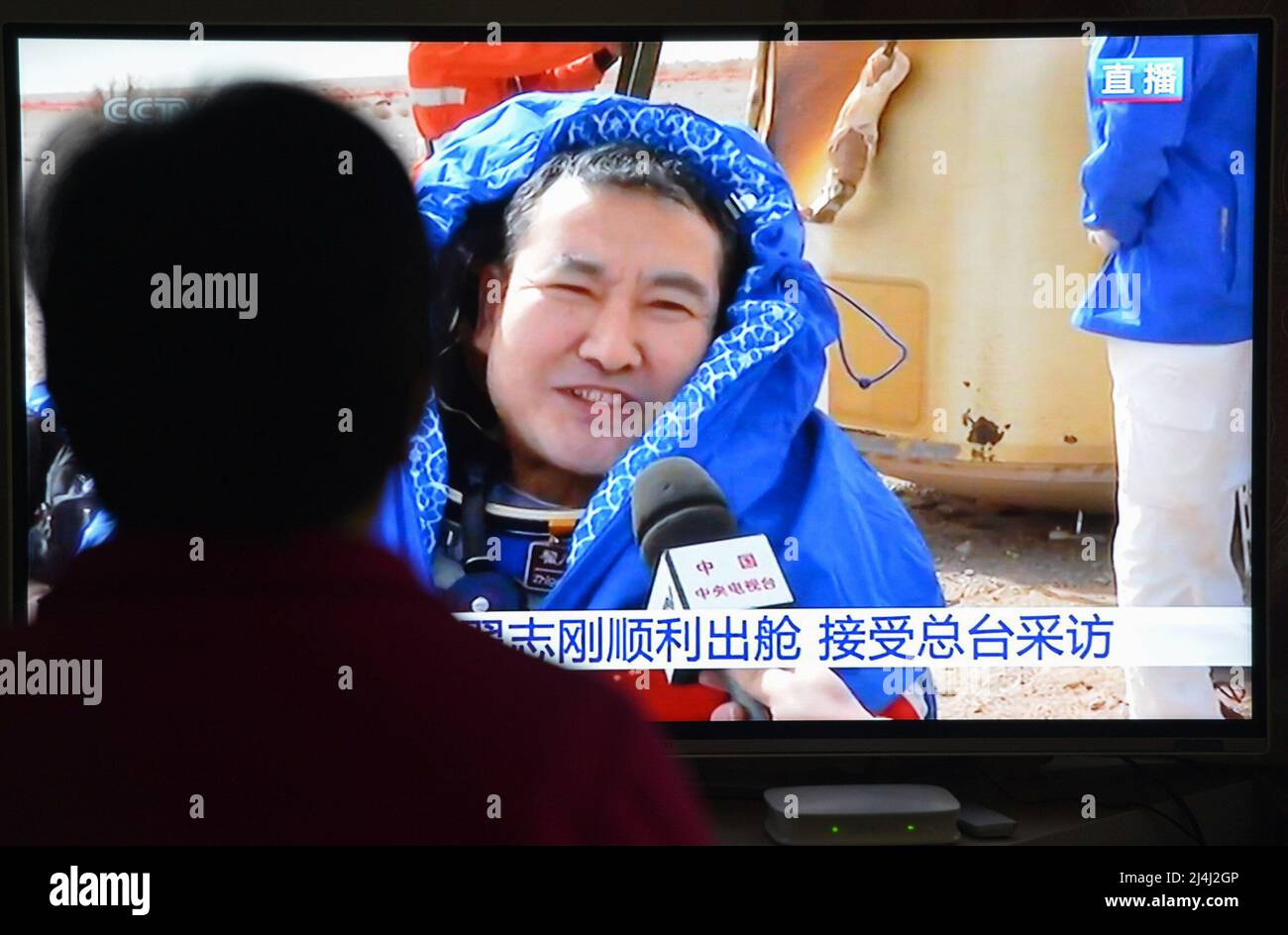 A woman watches a live TV broadcast of the successful landing of the Shenzhou XIII re-entry module. TV screen for the astronaut Zhai Zhigang. After orbiting Earth for six months, the three crew members of China's Shenzhou XIII mission have departed from the Tiangong space station and returned to the mother planet on Saturday morning, finishing the nation's longest manned spaceflight.Major General Zhai Zhigang, who was the mission commander, Senior Colonel Wang Yaping and Senior Colonel Ye Guangfu breathed fresh air for the first time after the half-year space journey as ground recovery personn Stock Photo