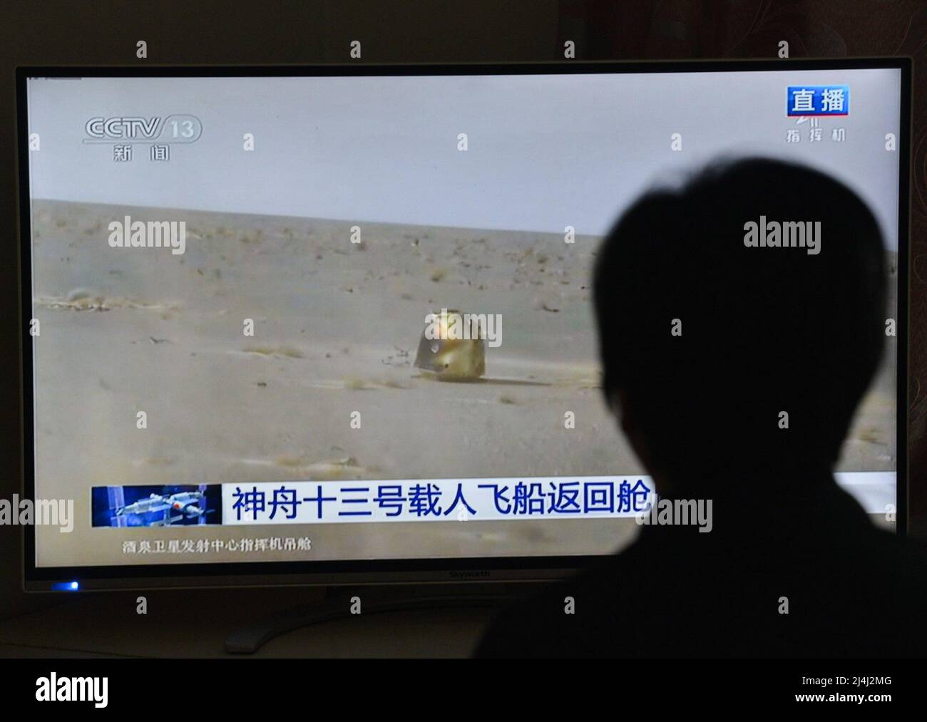 A woman watches a live TV broadcast of the successful landing of the Shenzhou XIII re-entry module. After orbiting Earth for six months, the three crew members of China's Shenzhou XIII mission departed from the Tiangong space station. They returned to the mother planet on Saturday morning, finishing the nation's longest human-crewed spaceflight. Major General Zhai Zhigang, the mission commander, Senior Colonel Wang Yaping, and Senior Colonel Ye Guangfu breathed fresh air for the first time after the half-year space journey as ground recovery personnel opened the hatch of their re-entry capsule Stock Photo