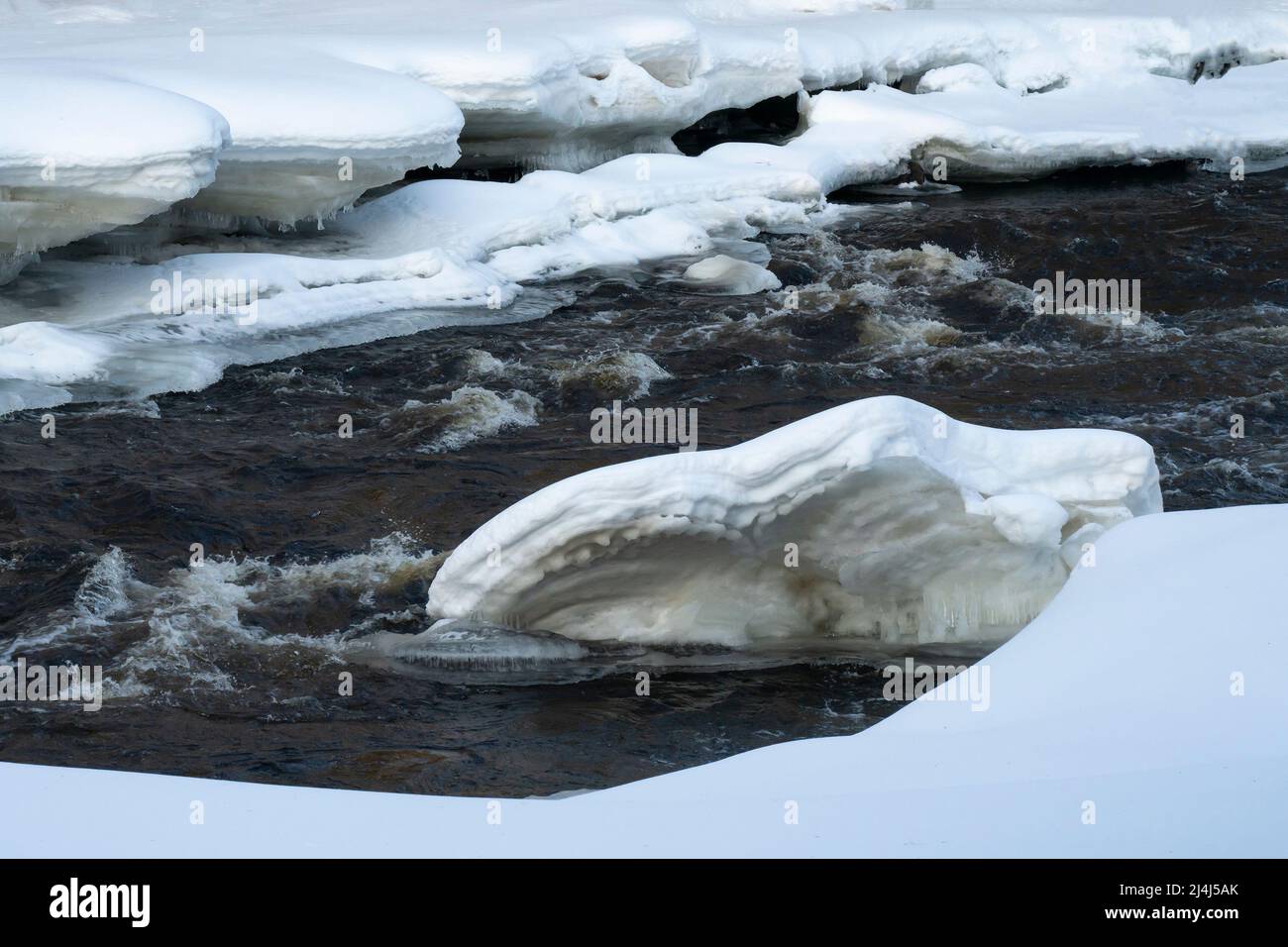 A mass of ice and snow breaks into the water of a thawing river Stock ...