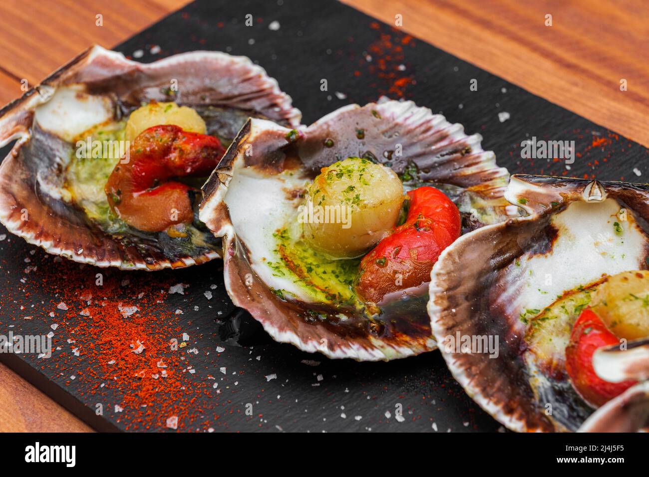 Cooked scallops on blackstone slate plate with species. Variety of