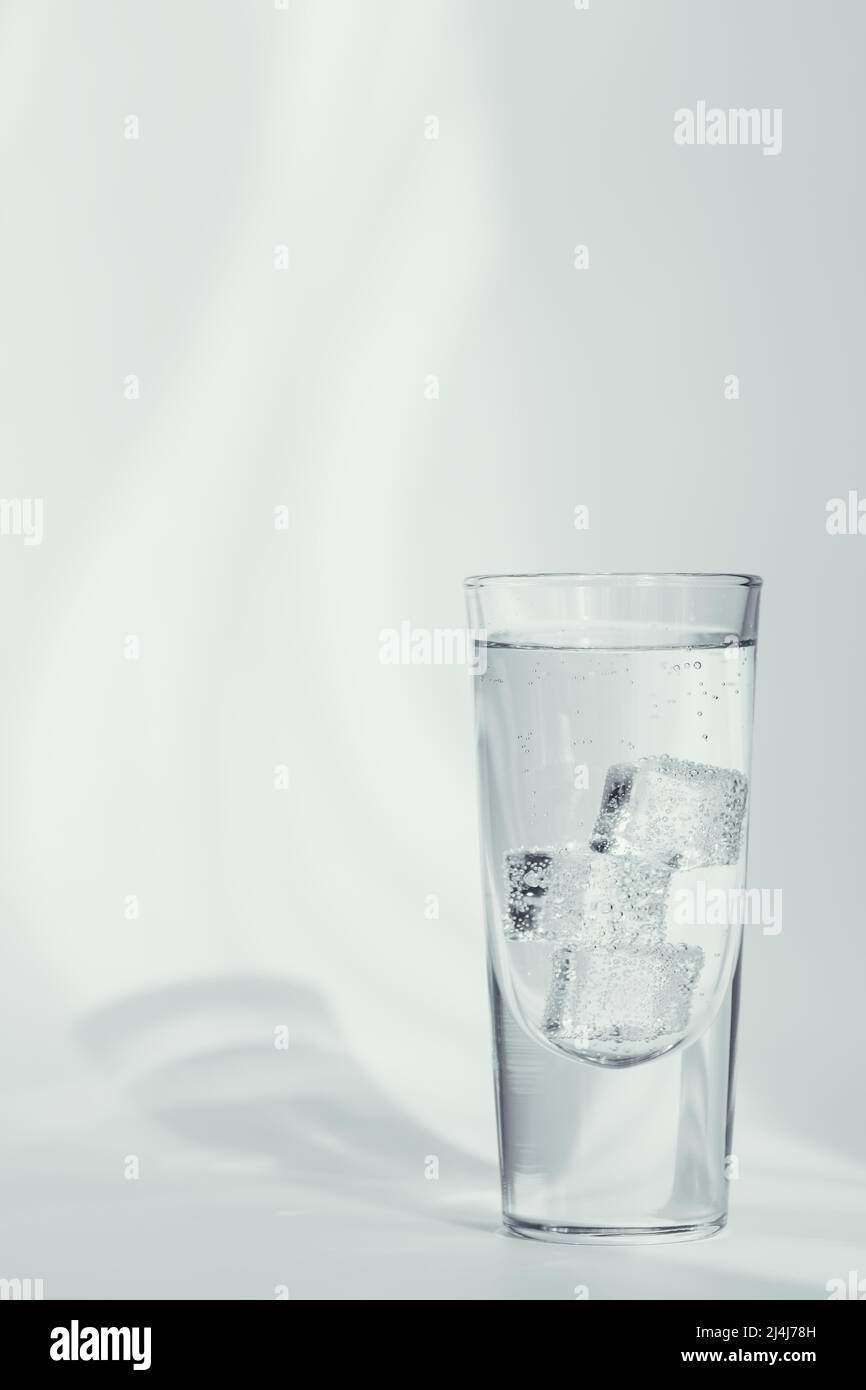 Glass of clean mineral sparkling water with ice on white background ...