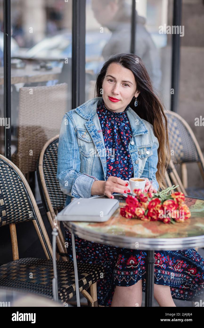 Attractive woman in a blue dress sitting in the street cafe and
