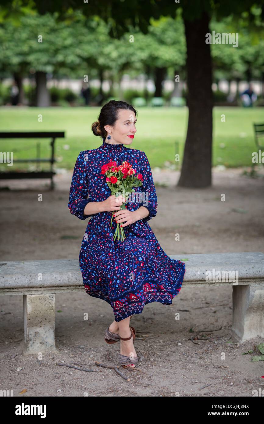 Attractive woman in a blue dress sitting in the park Stock Photo - Alamy