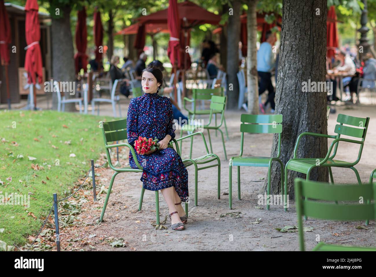 Attractive woman in a blue dress sitting in the park Stock Photo - Alamy