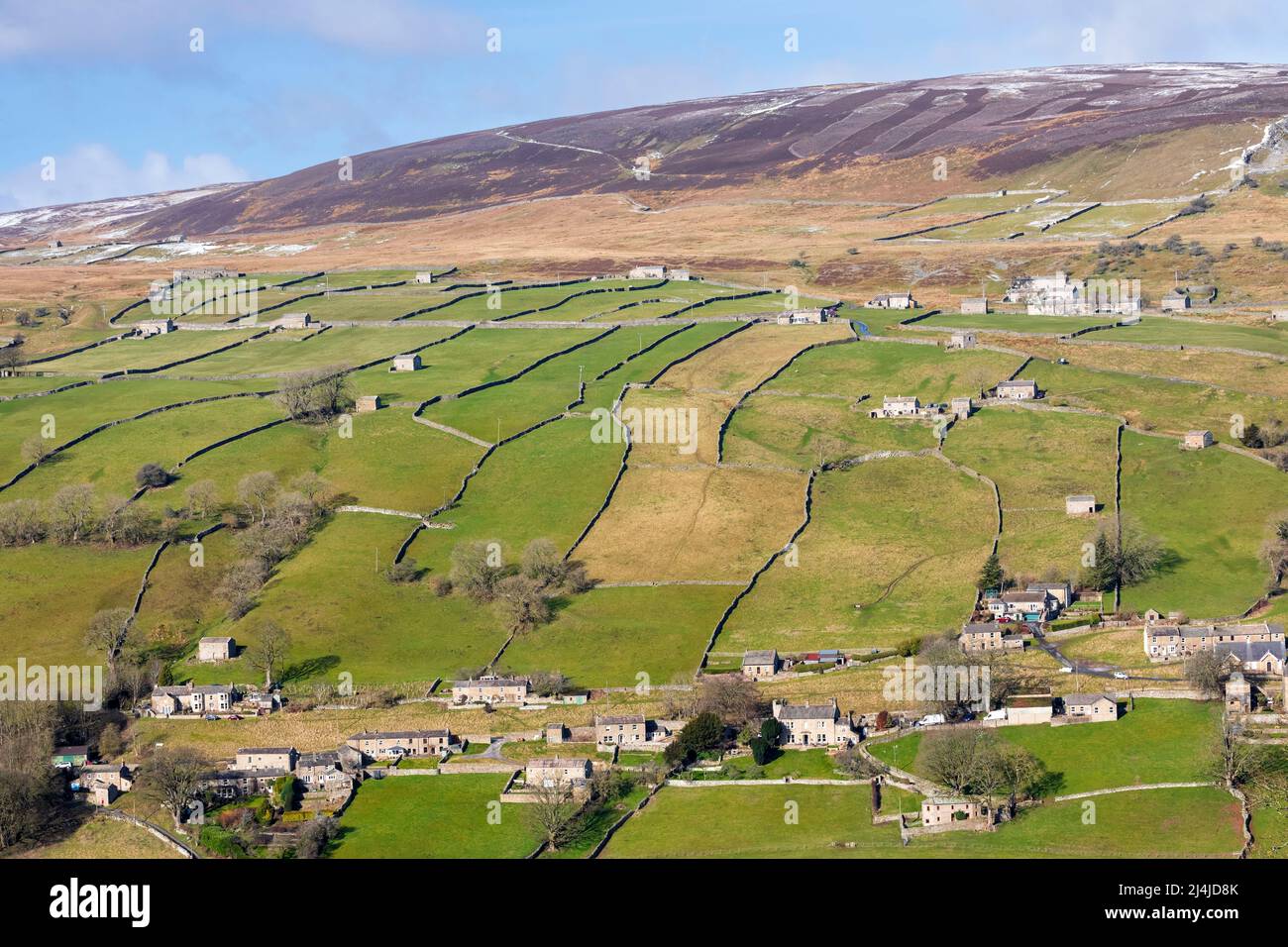 Swaledale, Yorkshire Dales National Park, Snow covered hills above a patchwork of dry stone wall lined fields and pastures with iconic stone barns in Stock Photo