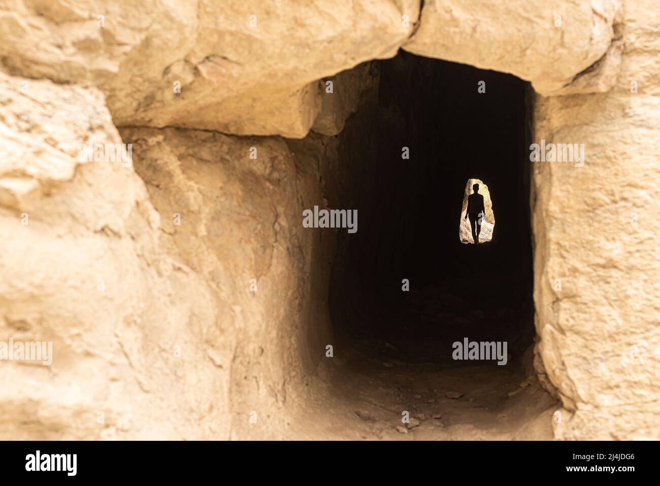 Anonymous woman in dark cave through mountain Stock Photo