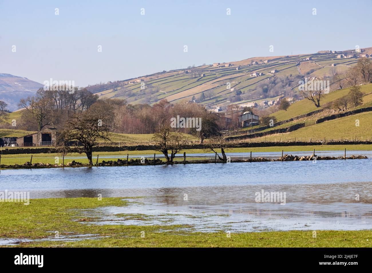 Flooded fields near Reeth in Swaledale, Yorkshire Dales National Park. Iconic stone barns and dry stone walls on the hillside above. Stock Photo