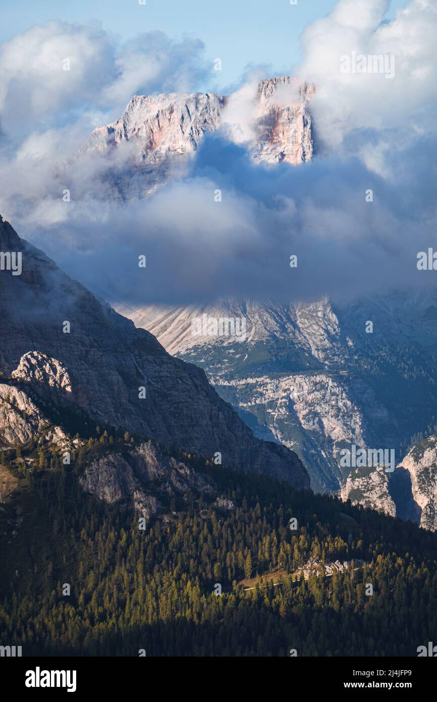 The peaks of the Dolomites, with the lights of the sunset, immersed in the fog, near the town of Cortina d'Ampezzo, Italy - October 2021. Stock Photo