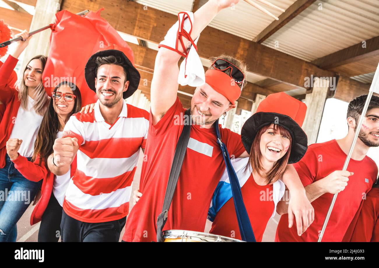 Football supporter fans friends cheering and walking to soccer cup match at intenational stadium - Young people group with red and white t-shirts Stock Photo