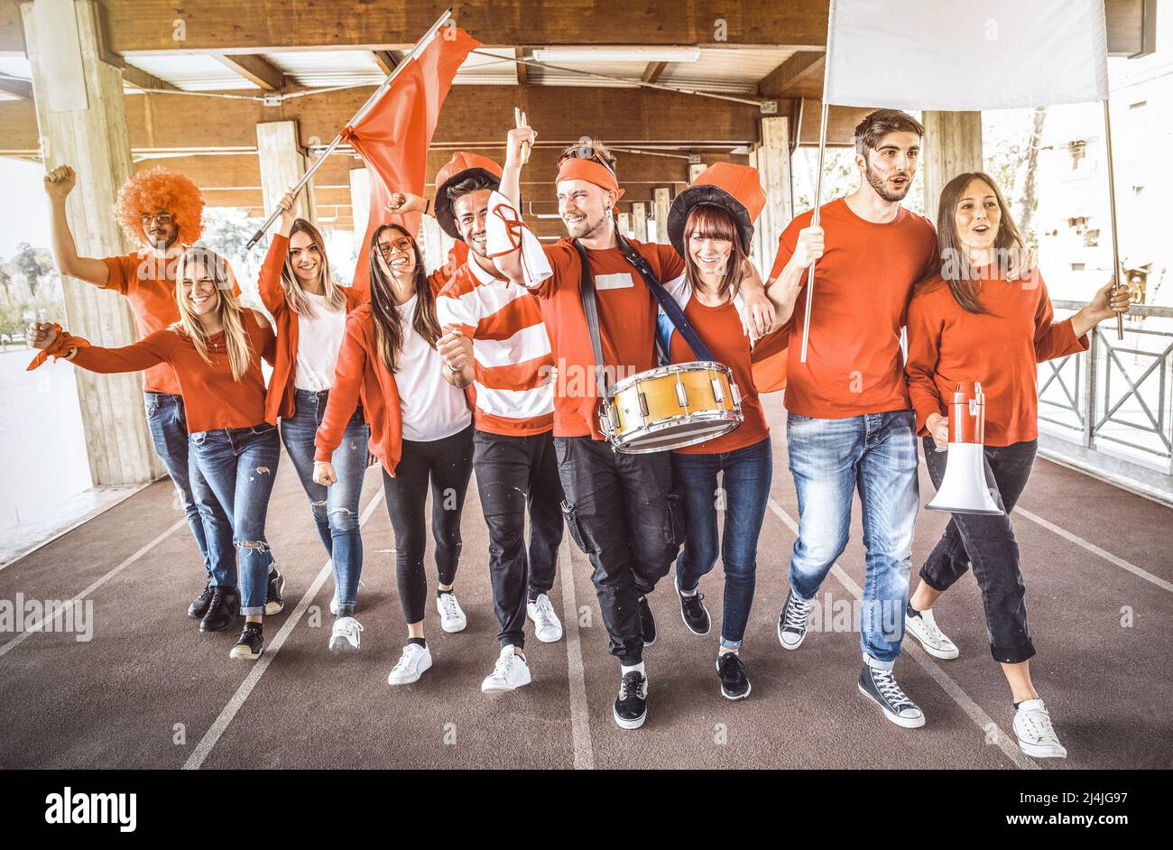 Football supporter fans friends cheering and walking to soccer cup match at intenational stadium - Young people group with red and white t-shirts havi Stock Photo