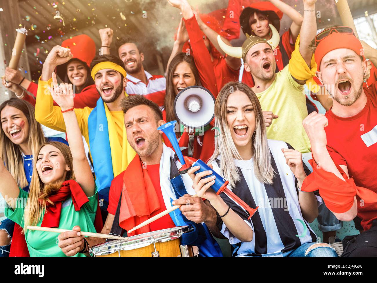 Football supporter fans friends cheering and watching soccer cup match at intenational stadium - Young people group with multicolored t-shirts Stock Photo