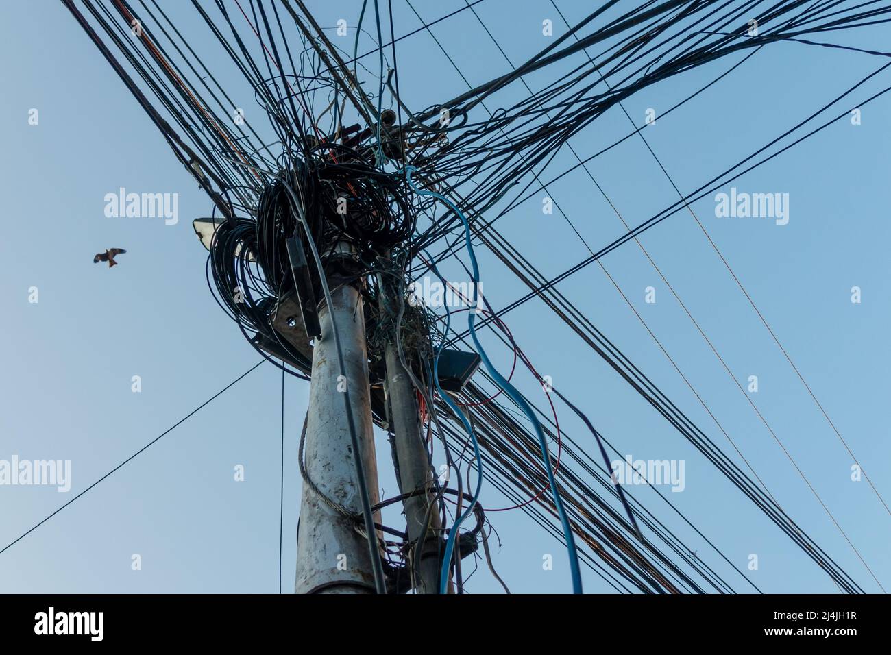 Electricity poles with overcrowded wires and distribution boxes in India. Stock Photo