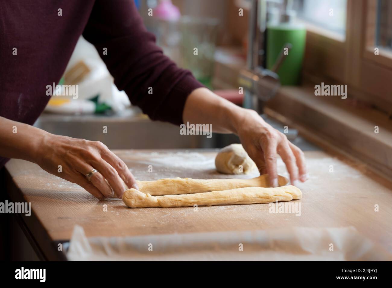 female hands roll and shape dough to bake an easter braid Stock Photo