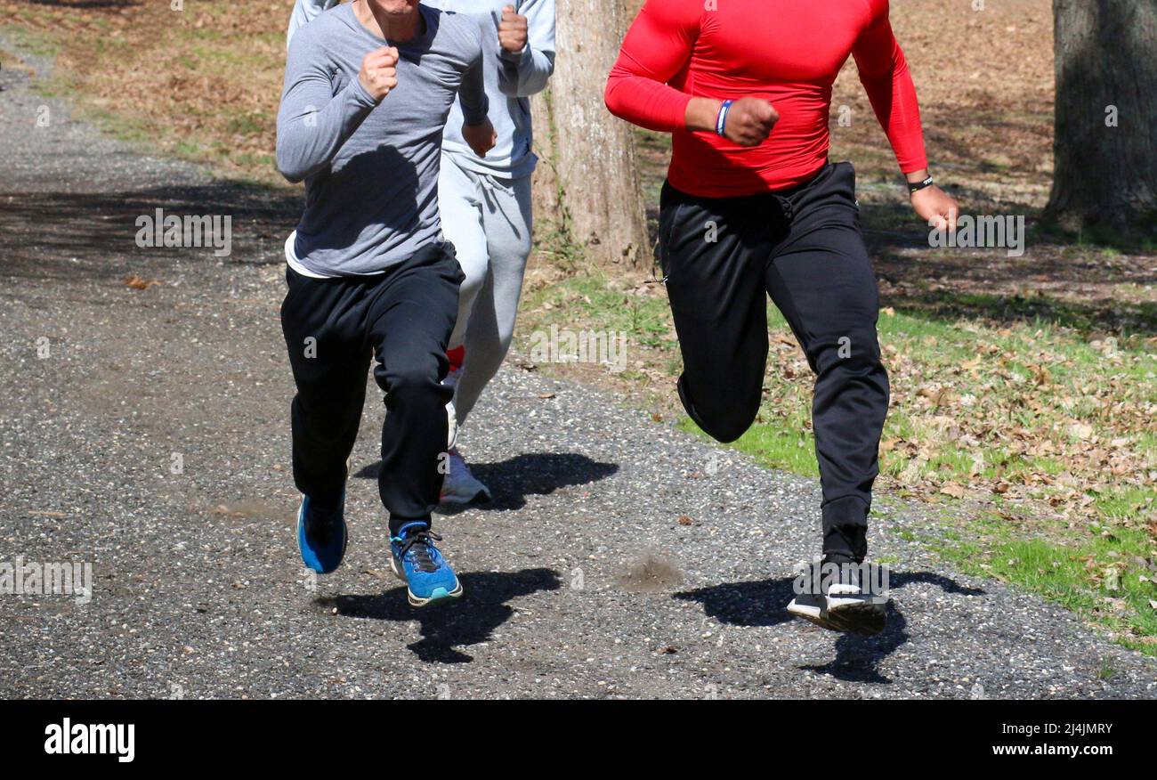 Three high school track runners running fast on an uphill trail in the