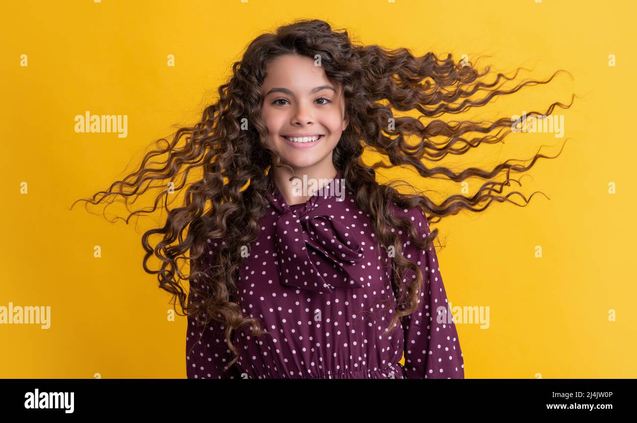 glad girl with long brunette curly hair on yellow background Stock ...