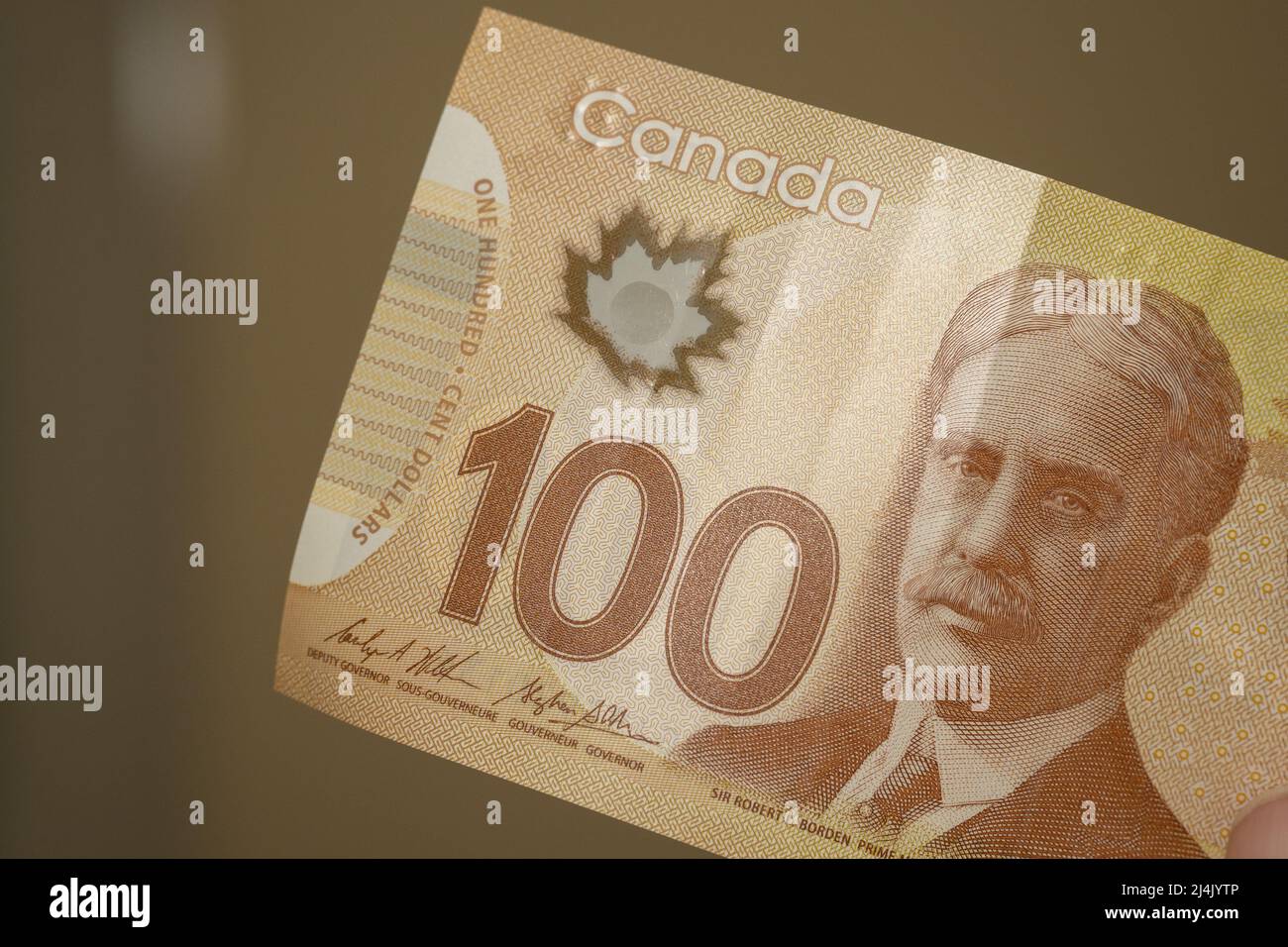Currency of the Canada - One brown hundred dollar notes spread out on a  brown background. Money exchange Stock Photo - Alamy