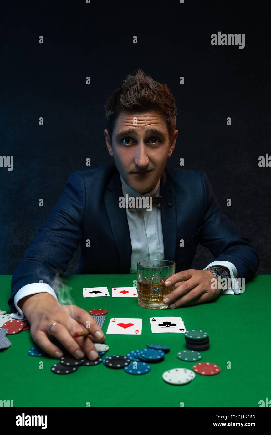 Poker player with cards and chips at green table in casino. Stock Photo