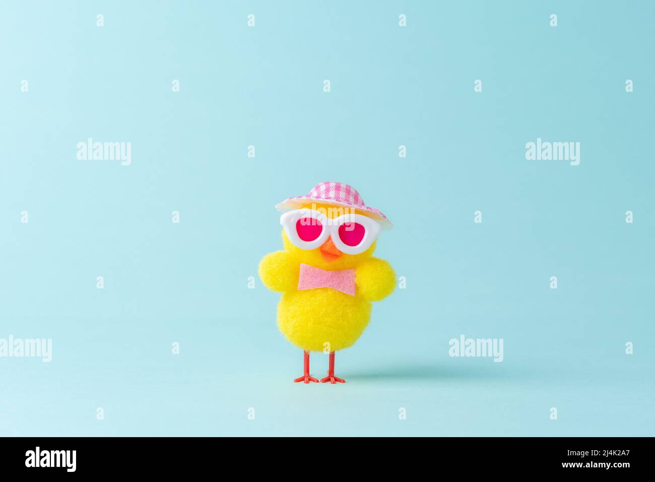 Funny chicken with hat on blue background. Spring Easter minimal concept. Stock Photo