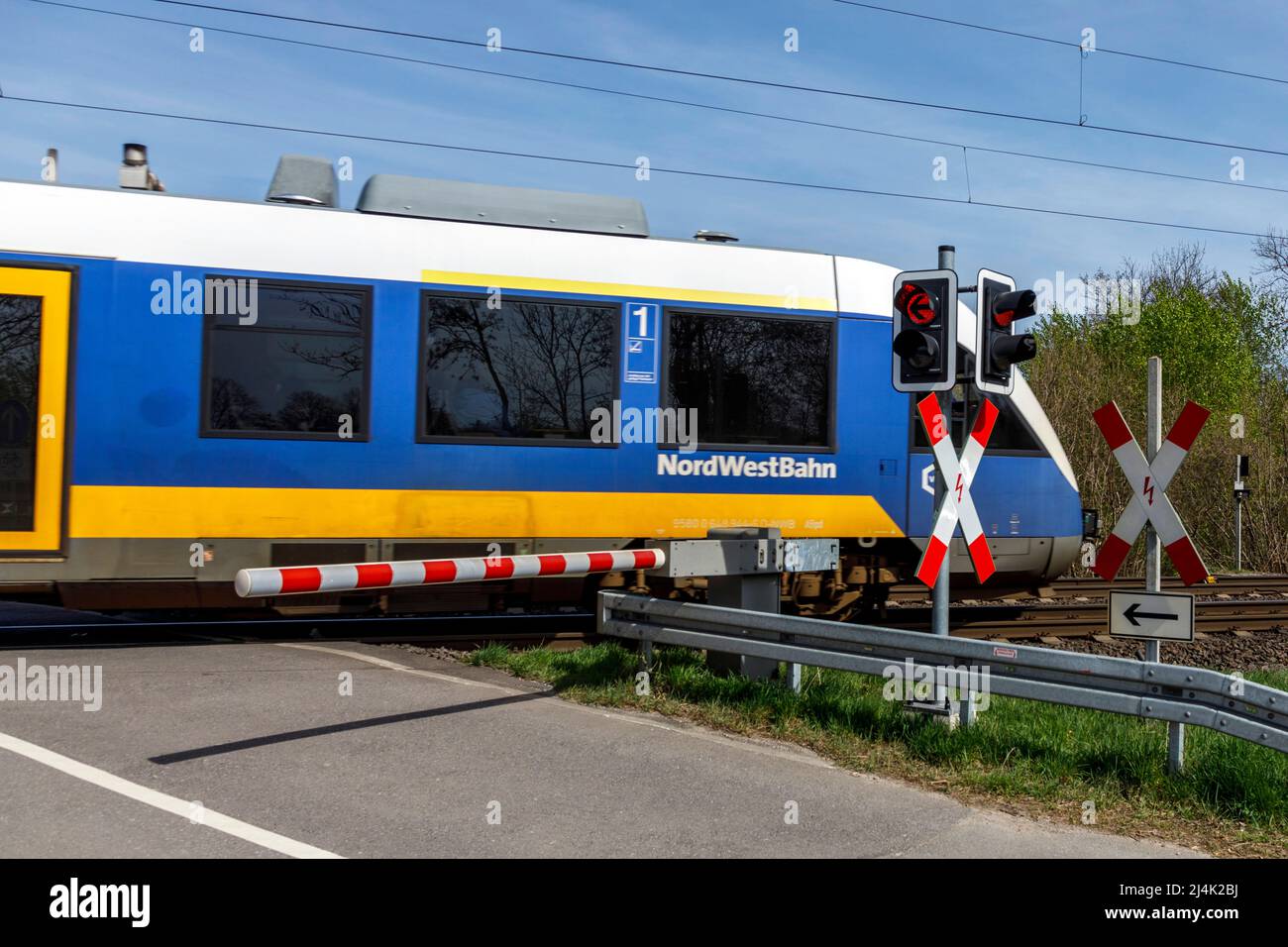 NordWestBahn drives through a level crossing with barriers Stock Photo