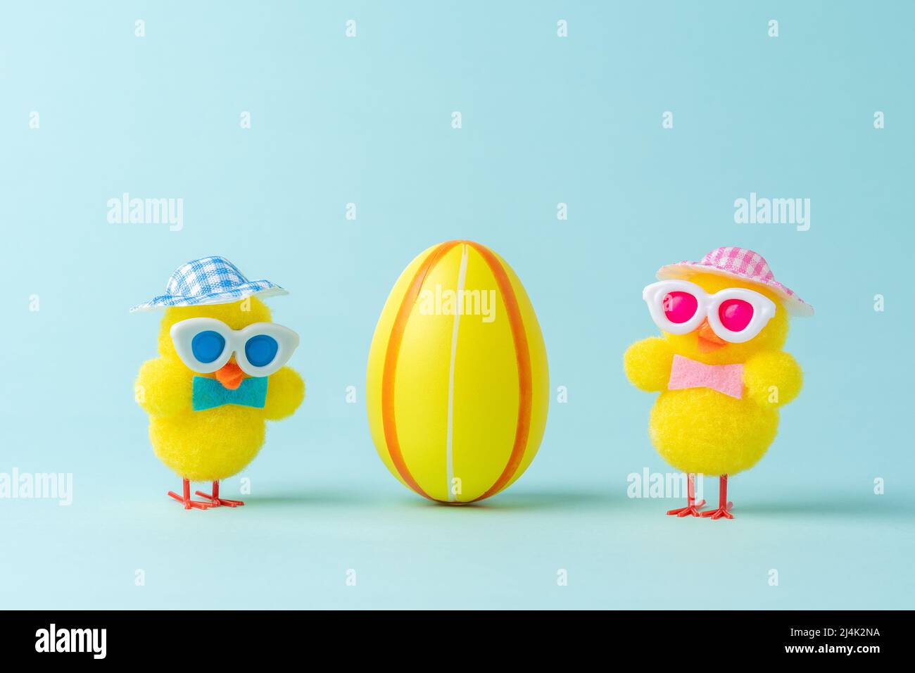Two chickens with colorful easter egg on blue background. Easter minimal concept. Creative Happy Easter or spring layout. Stock Photo