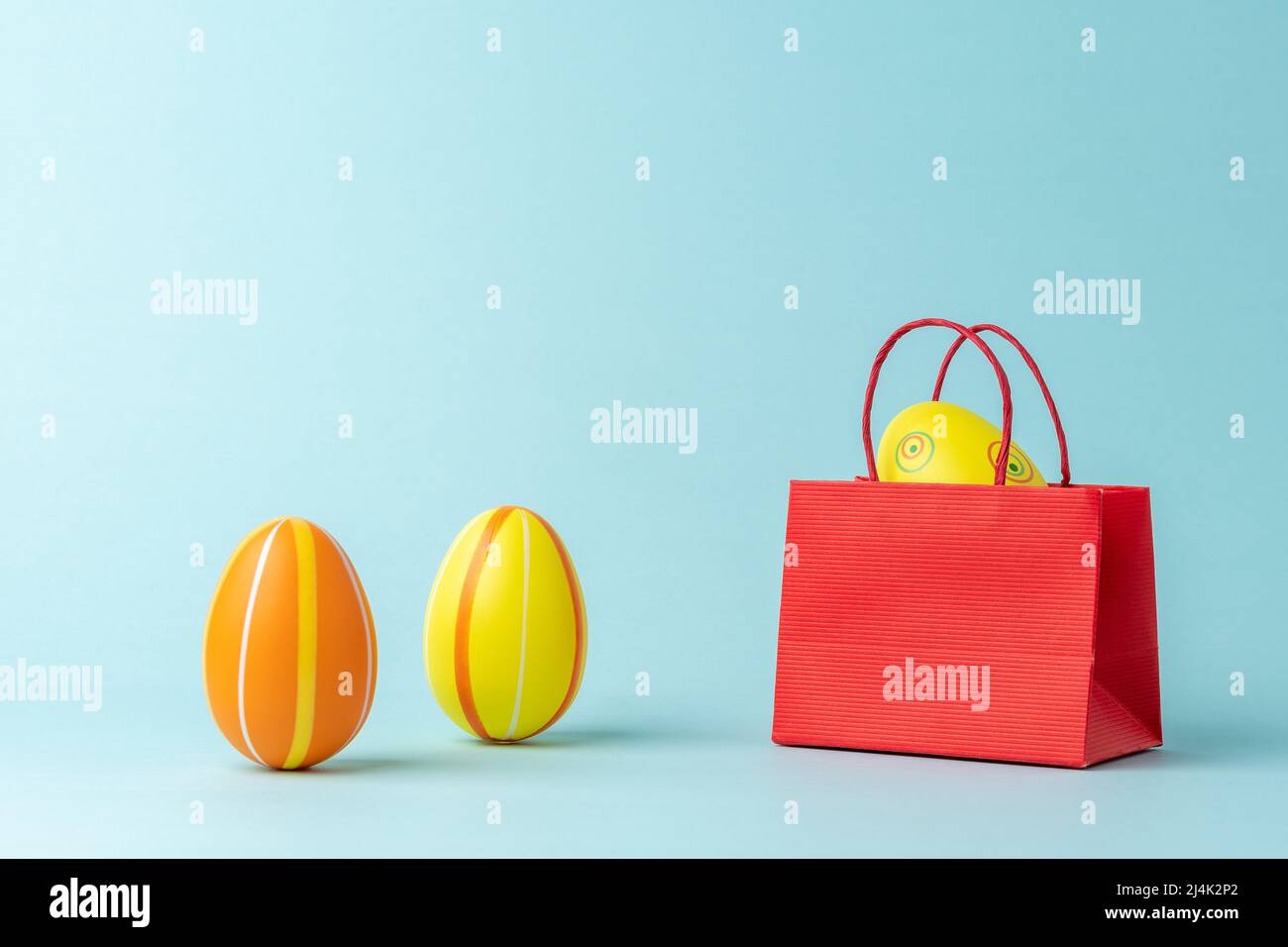 Easter egg in shopping bag on blue background. Easter minimal concept. Creative Happy Easter or spring layout. Stock Photo