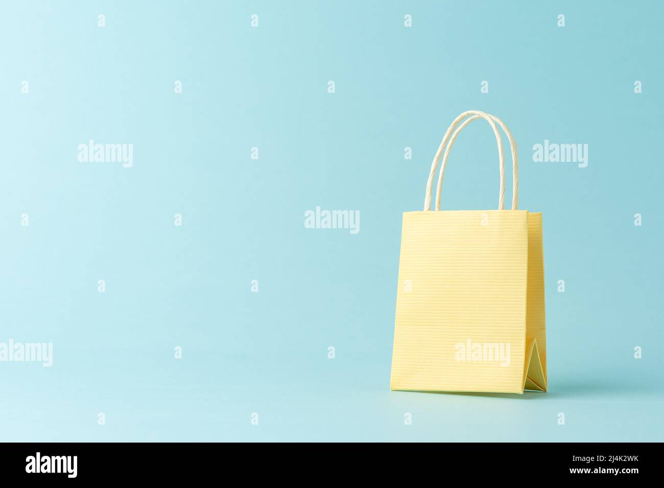 Yellow shopping bag on blue background. Creative minimal shopping concept. Stock Photo
